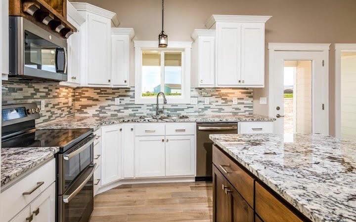 White kitchen with granite island in the Jaxon Subdivision